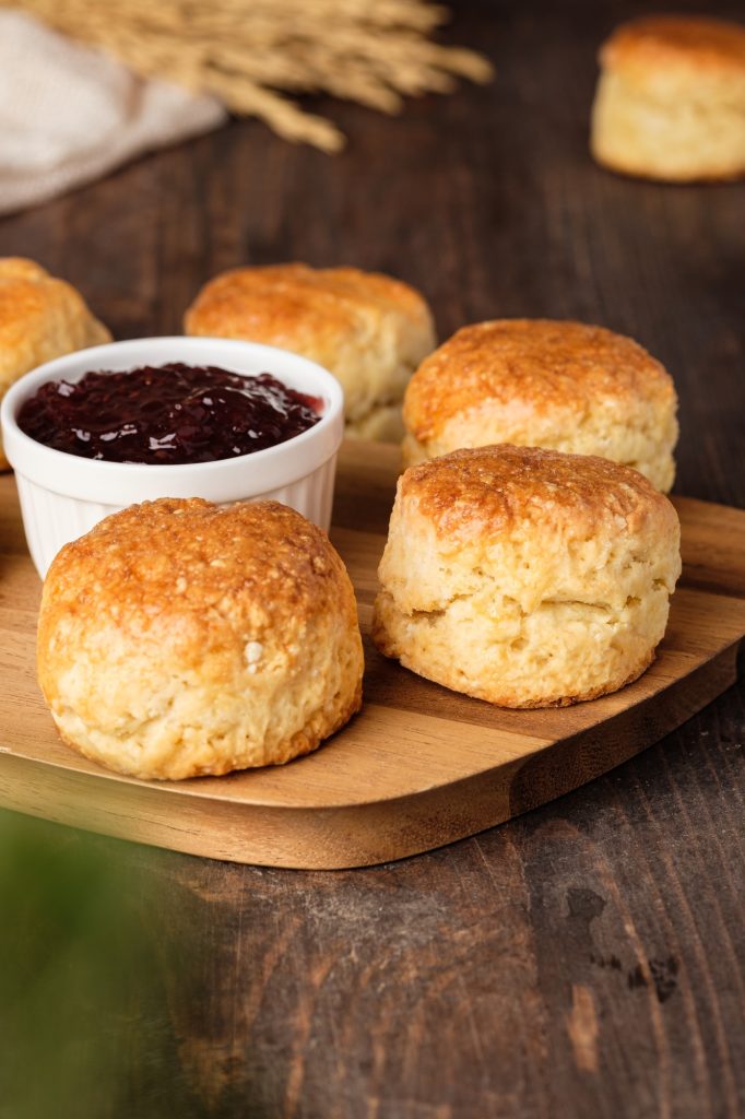 group of scones on wood plate with jam on table